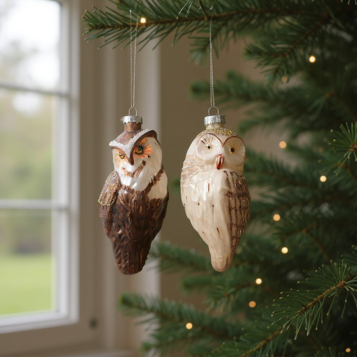Due decorazioni di vetro a forma di gufo appese all'albero di Natale