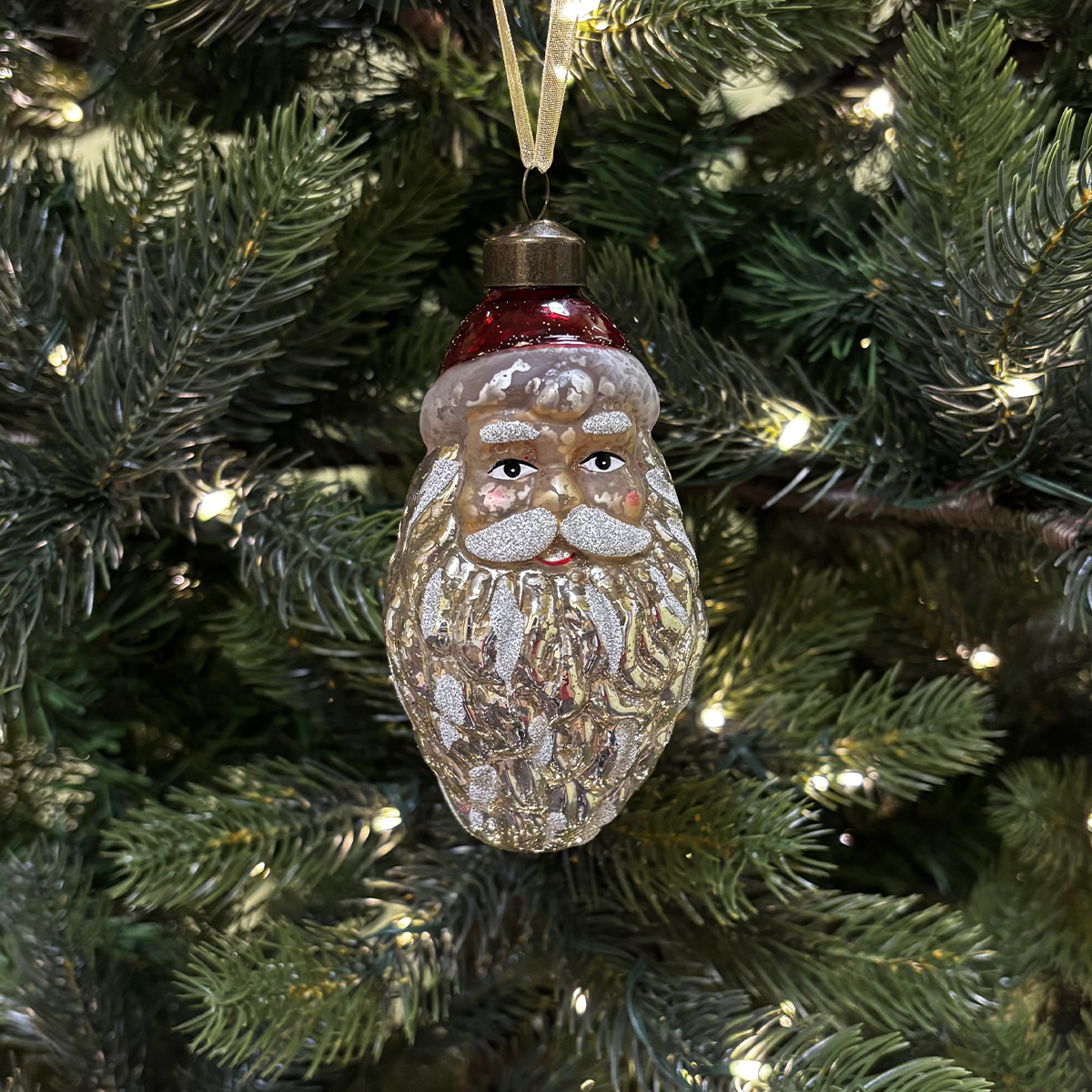 Ornement de Père Noël en verre sur un sapin de Noël illuminé