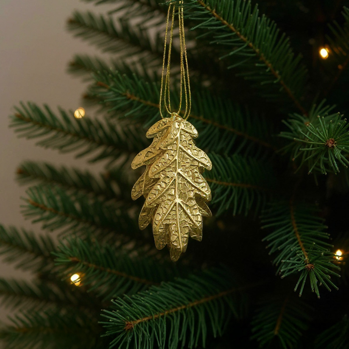 Ornement doré en forme de feuille de chêne sur un sapin de Noël