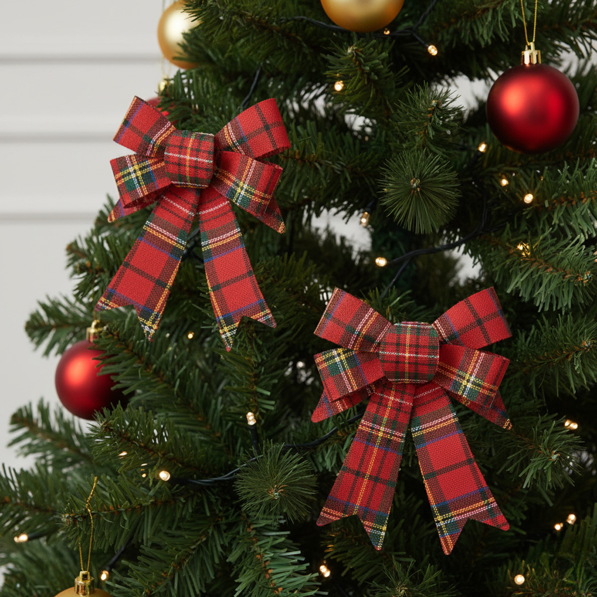 Deux nœuds écossais rouges sur un sapin de Noël décoré