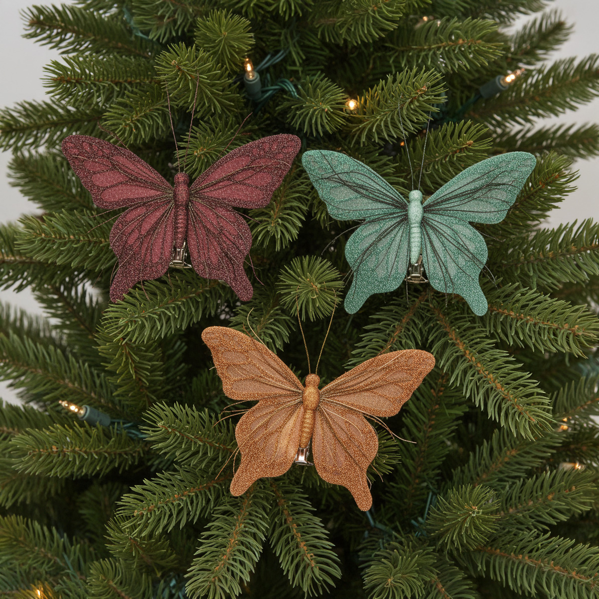 Tre decorazioni a forma di farfalla scintillanti su un albero di Natale