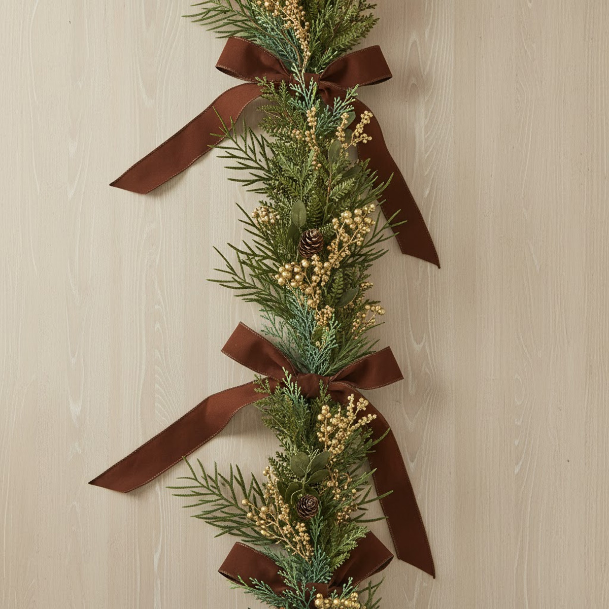 Christmas garland with fir branches, golden berries and brown bows