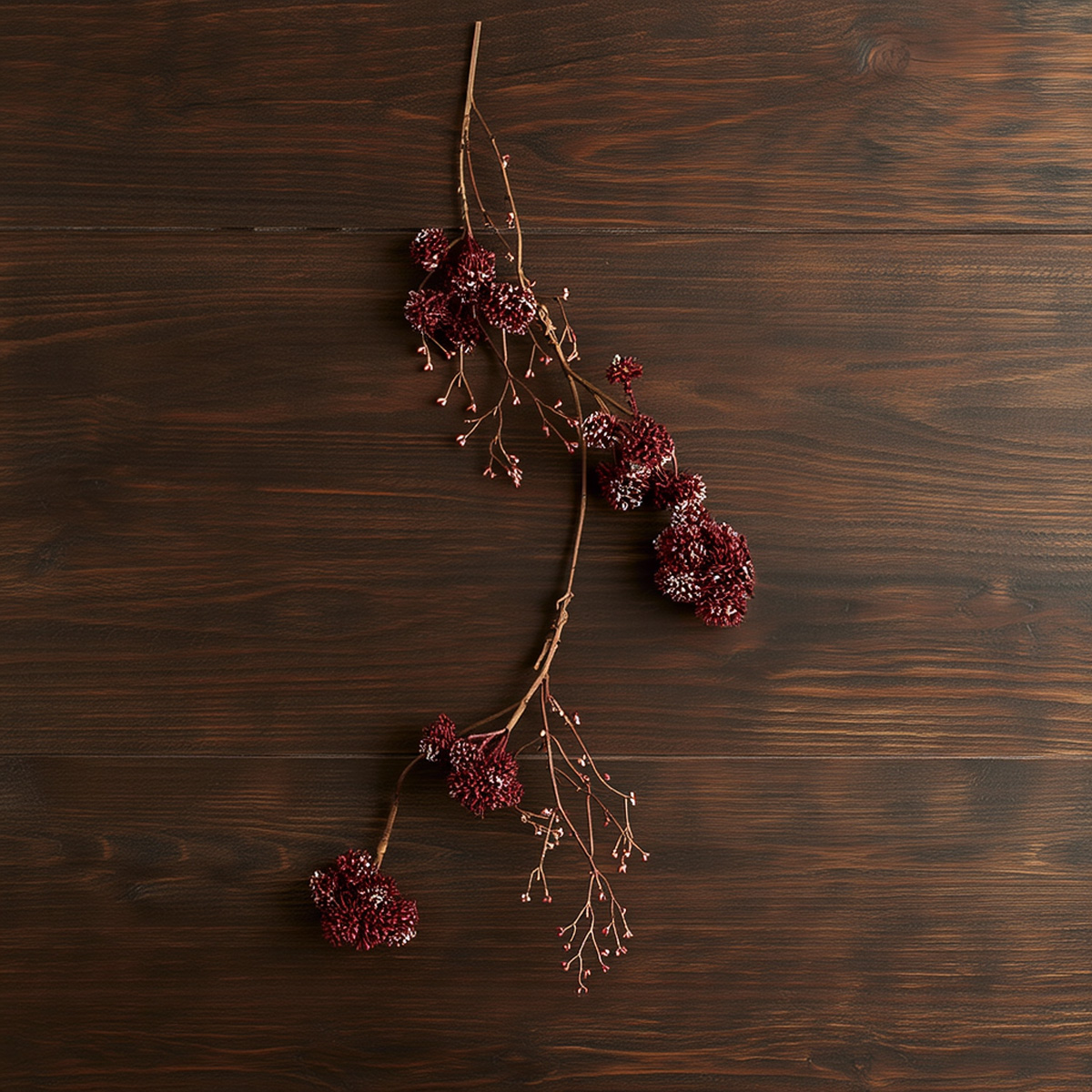 Ramo di fiori artificiali bordeaux su sfondo di legno scuro
