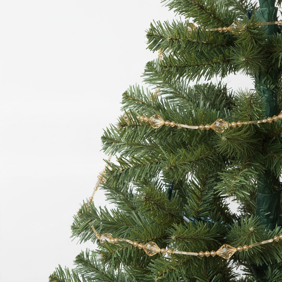Guirlande de perles dorées sur un sapin de Noël artificiel