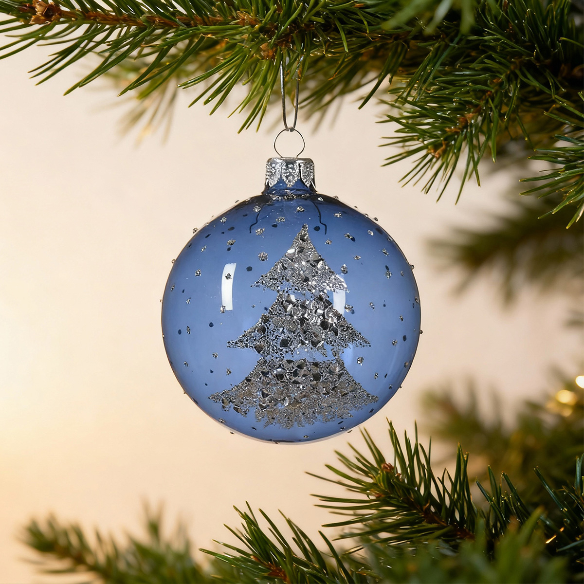 Boule de Noël bleue avec un sapin argenté scintillant sur une branche de sapin