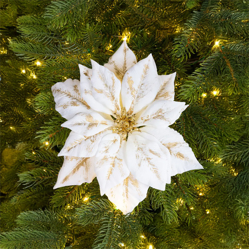 Witte kerstster met gouden accenten op een kerstboom met lichtjes