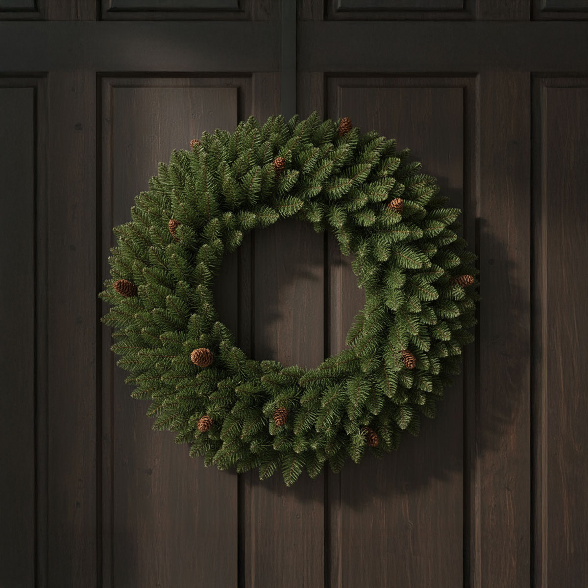 Couronne de sapin avec pommes de pin sur une porte en bois sombre
