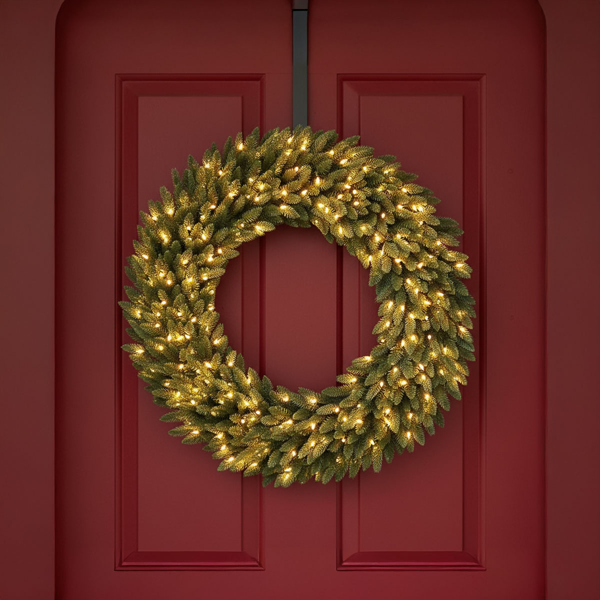 Couronne de Noël illuminée sur une porte rouge