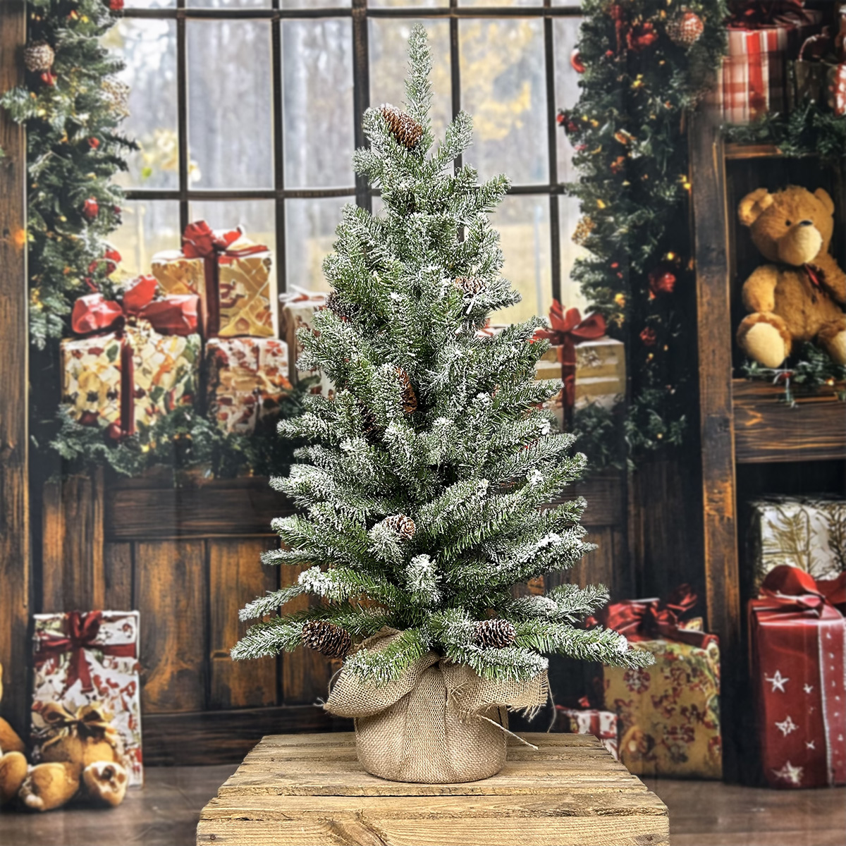 Petit arbre de Noël avec des pommes de pin et de la neige, sur une table en bois dans une ambiance festive.