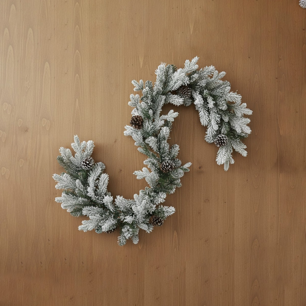Snowy Christmas wreath with pine cones on a wooden background
