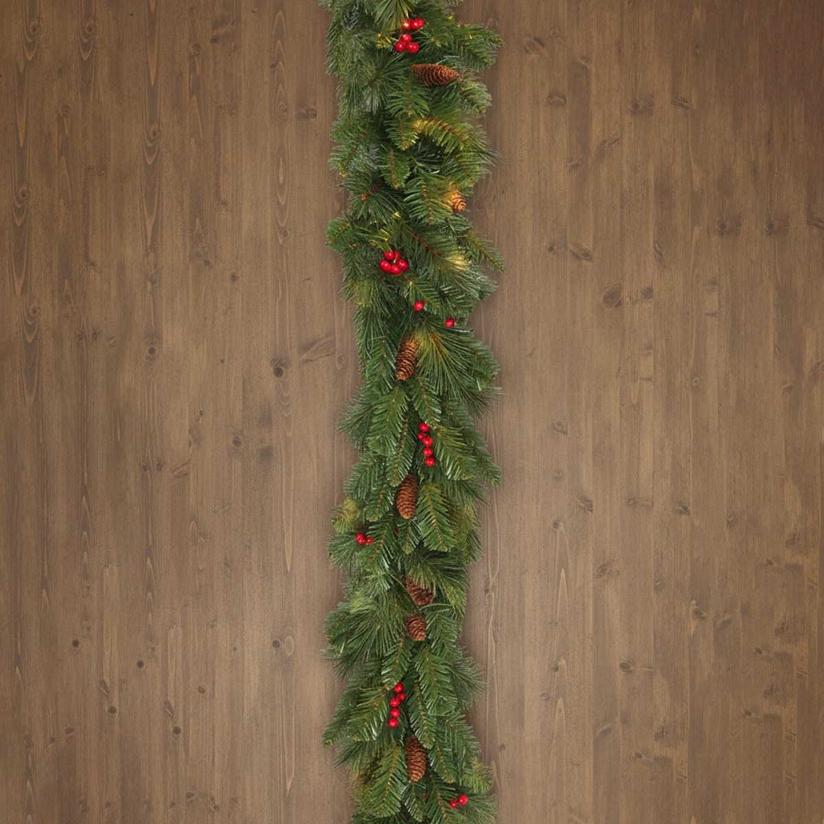 Guirlande de Noël verte avec des pommes de pin et des baies rouges sur fond de bois