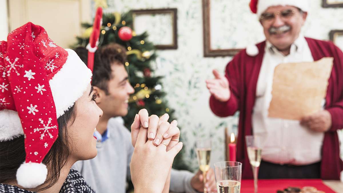 Famille célébrant Noël, avec une personne lisant un message, une bouteille et un verre de champagne.