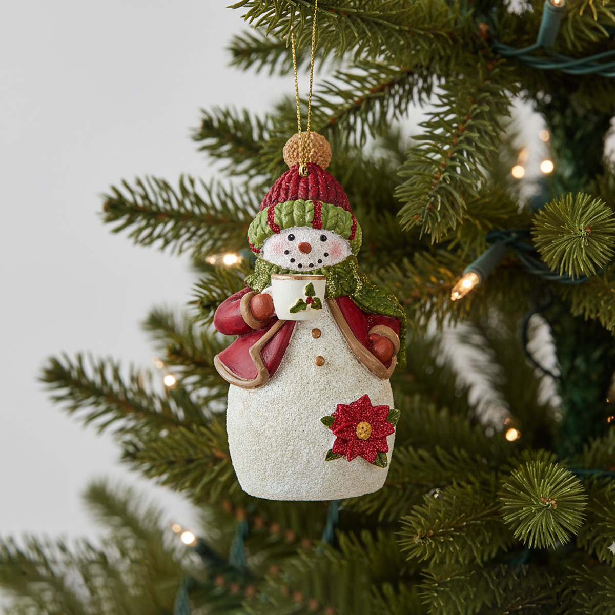 Snowman ornament with a mug of hot chocolate on a Christmas tree