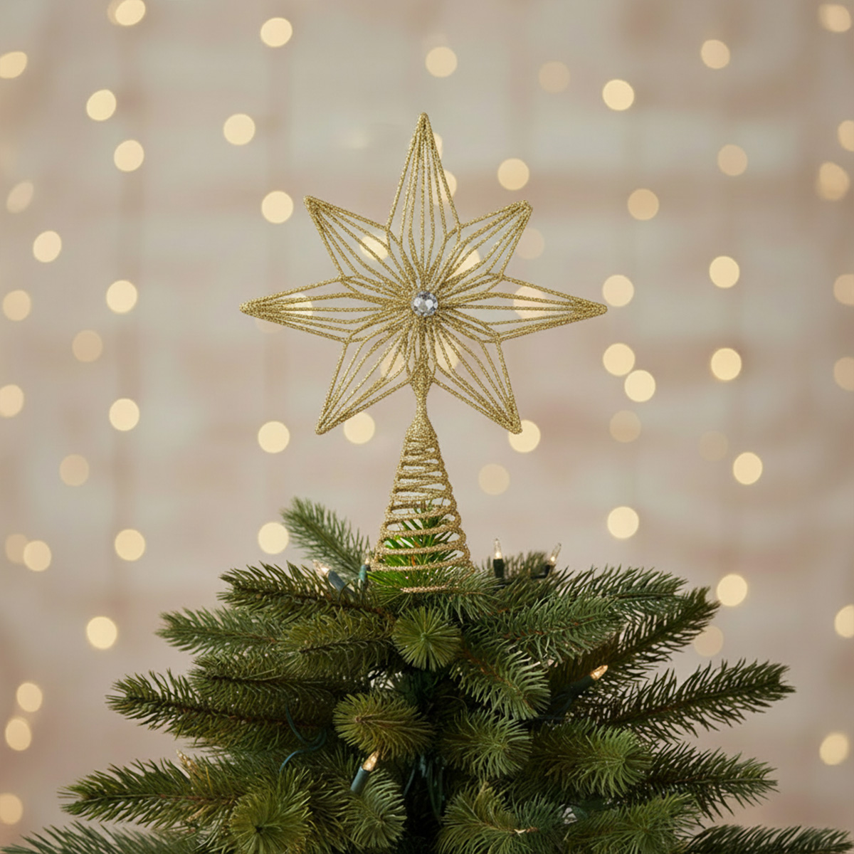 Pointe d'arbre de Noël dorée en forme d'étoile avec des lumières floues en arrière-plan