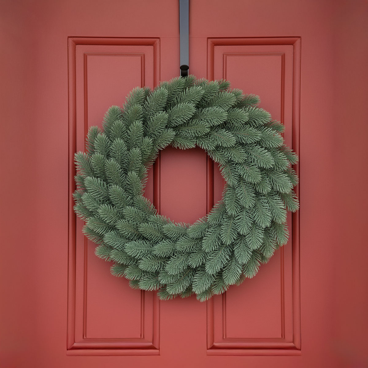 Couronne de sapin vert suspendue à une porte rouge