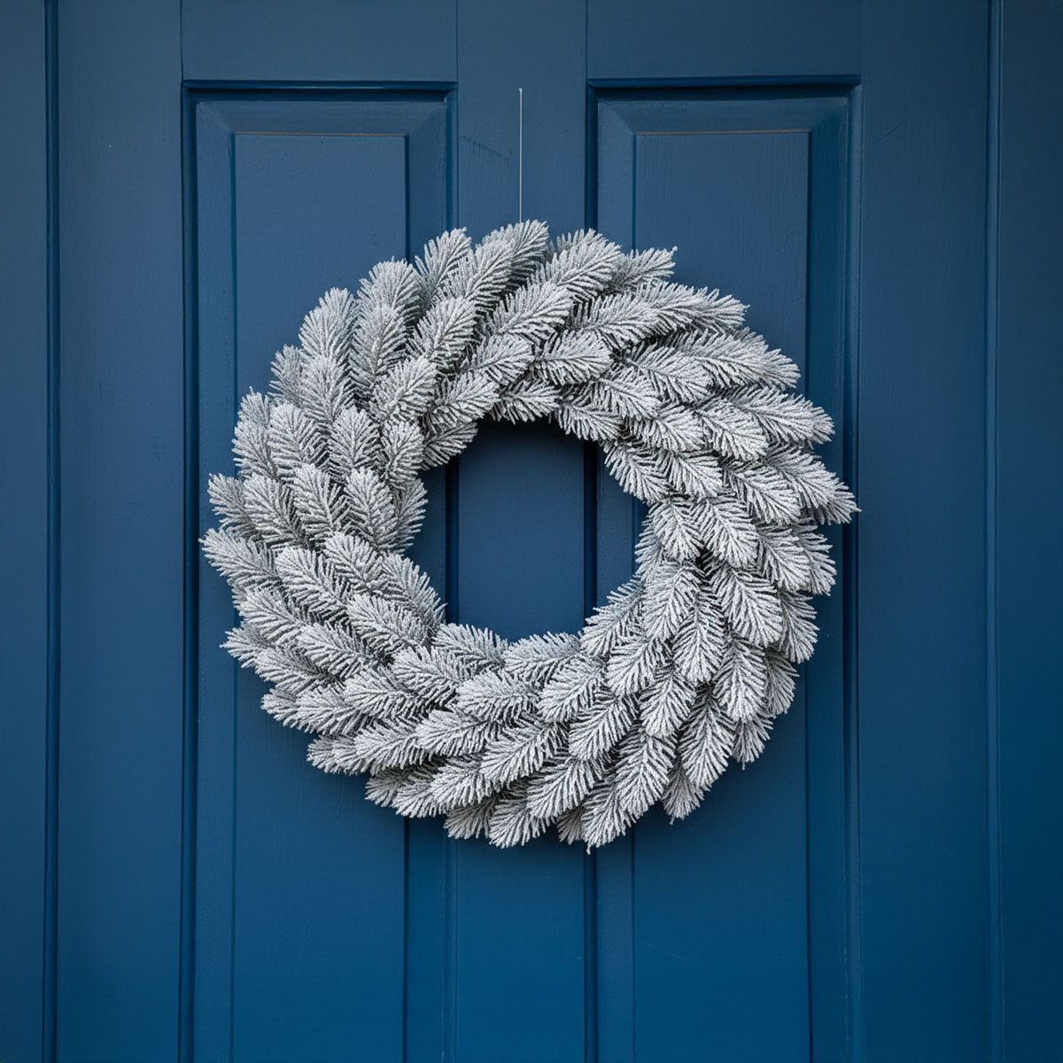 Couronne de sapin givrée sur une porte bleue