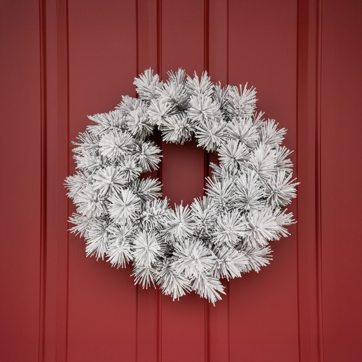 Couronne de sapin givrée sur une porte rouge