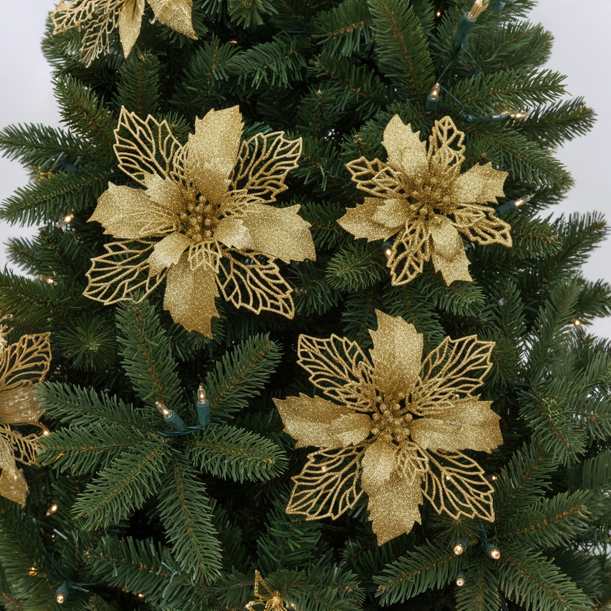 Fiori di stella di Natale dorati e scintillanti su un albero di Natale verde