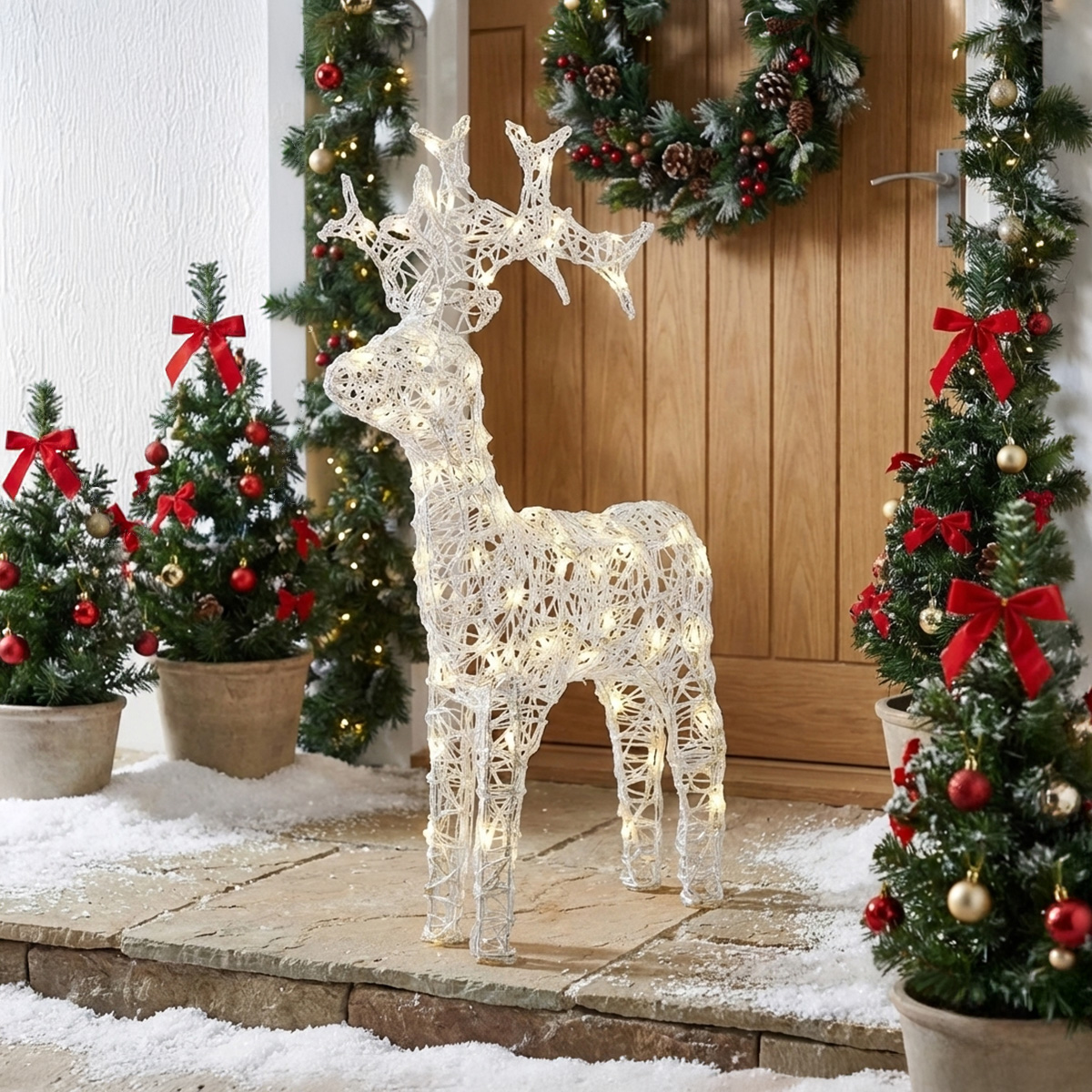 Renard lumineux de Noël devant une porte en bois décorée