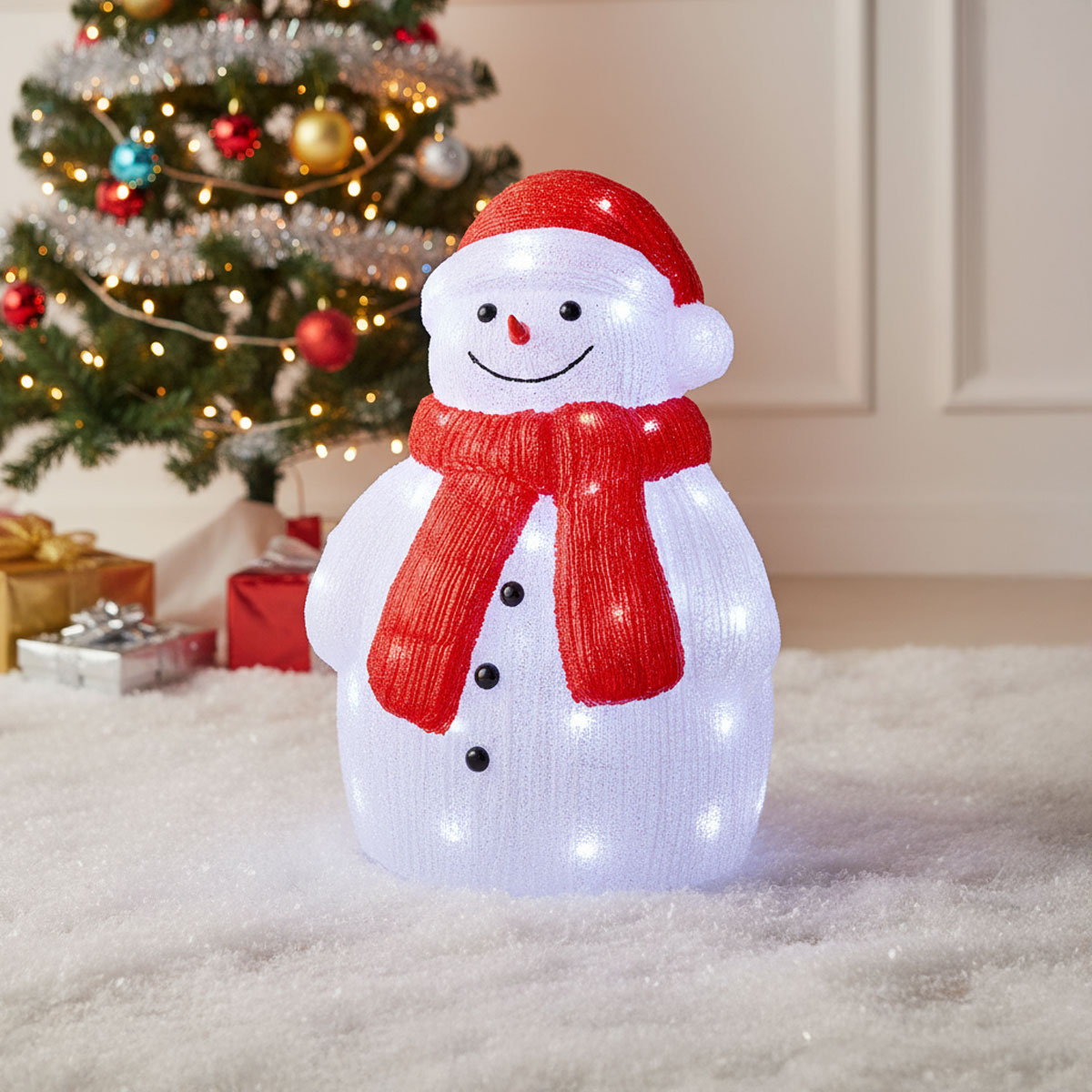 Bonhomme de neige lumineux avec un bonnet et une écharpe rouges, près d'un sapin de Noël