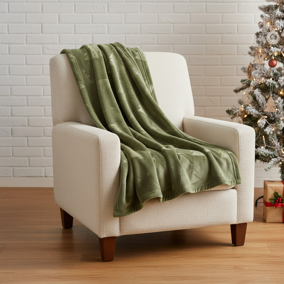Couverture verte à motifs d'arbres sur un fauteuil blanc à côté d'un sapin de Noël