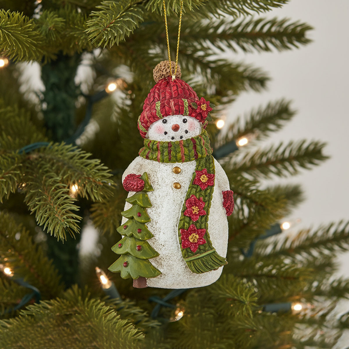 Snowman ornament with a red hat and green scarf on a Christmas tree