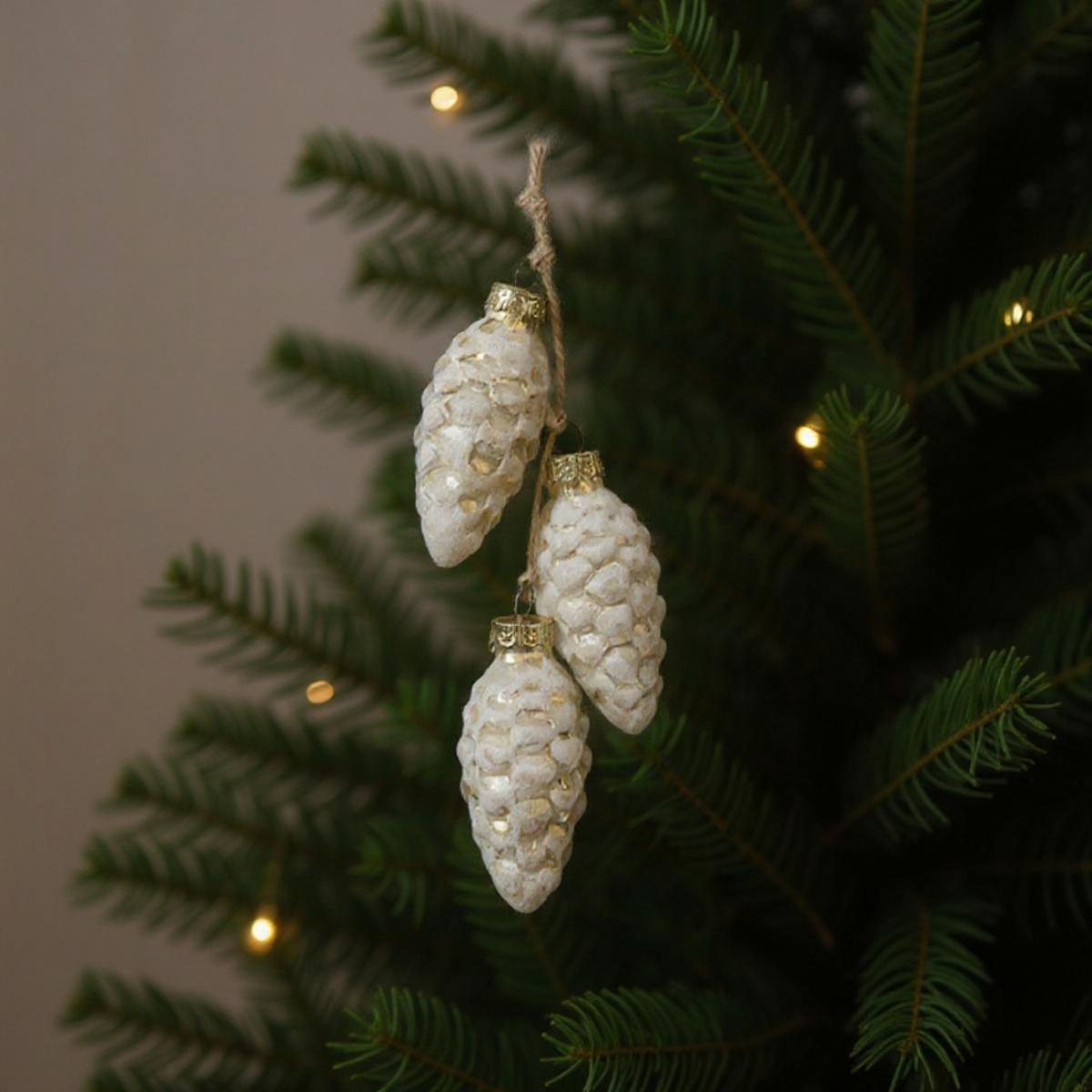 Décorations de pommes de pin blanches sur un sapin de Noël avec des lumières douces