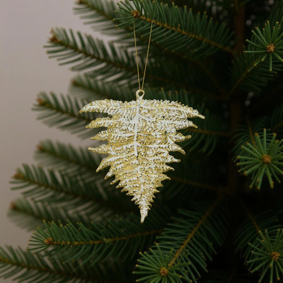 Ornement de feuille de fougère dorée et blanche suspendu à un sapin de Noël