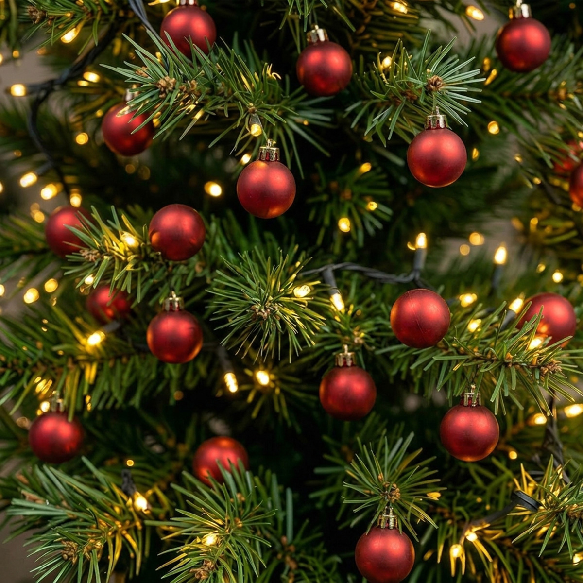 Boules de Noël rouges sur un sapin décoré de guirlandes lumineuses