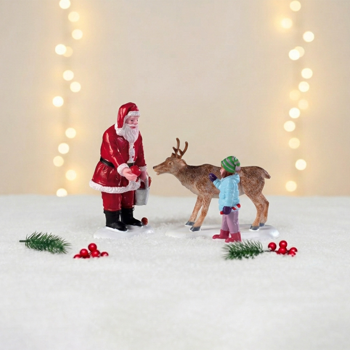 Figurine de Père Noël donnant à manger à un renne, avec une enfant et des décorations de Noël